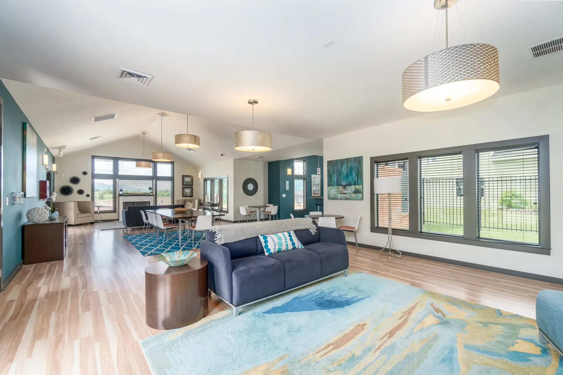 Modern apartment community lounge with sofas, tables, and a fireplace.