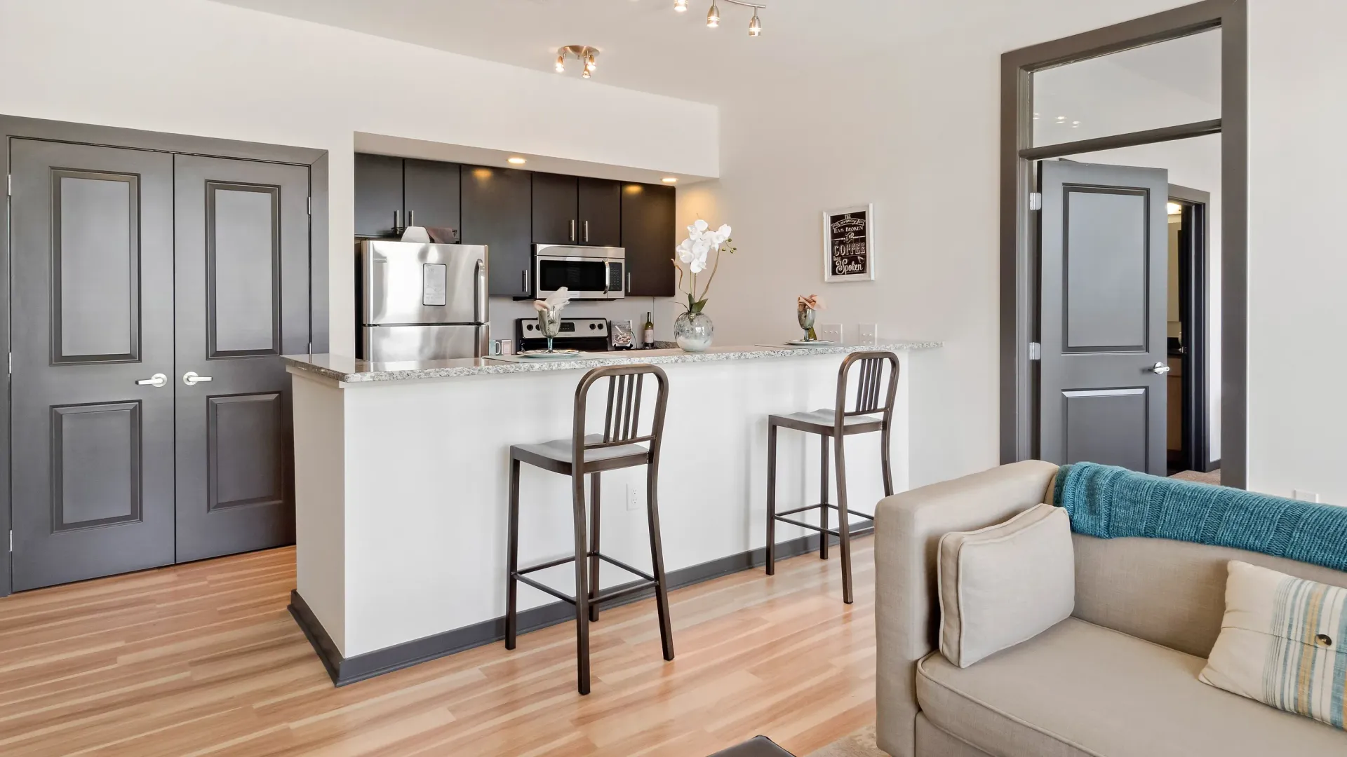 Modern kitchen with stainless steel appliances and a breakfast bar with two stools.