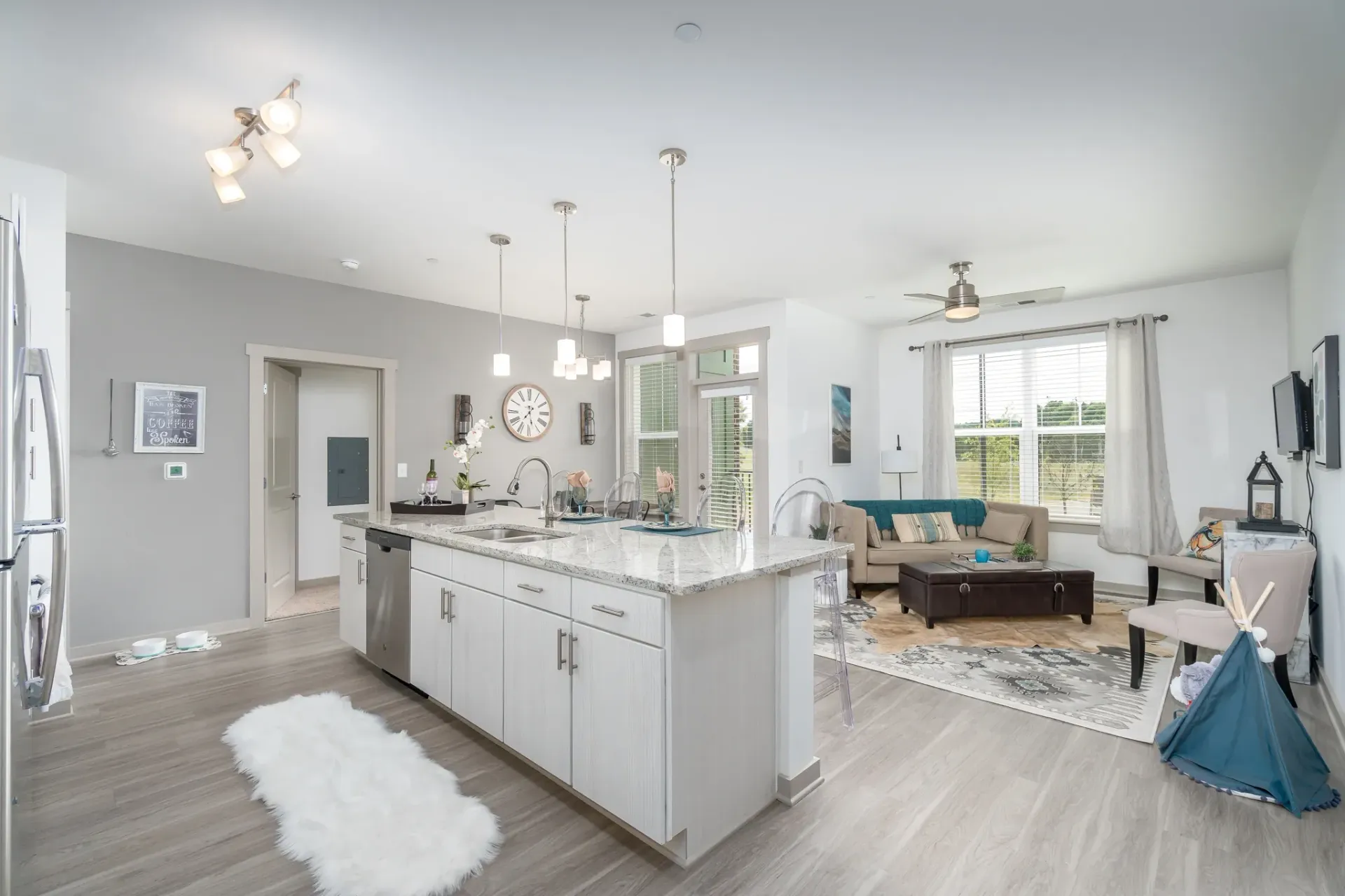 Modern open-concept kitchen with island, living area with sofa and coffee table, and large windows.