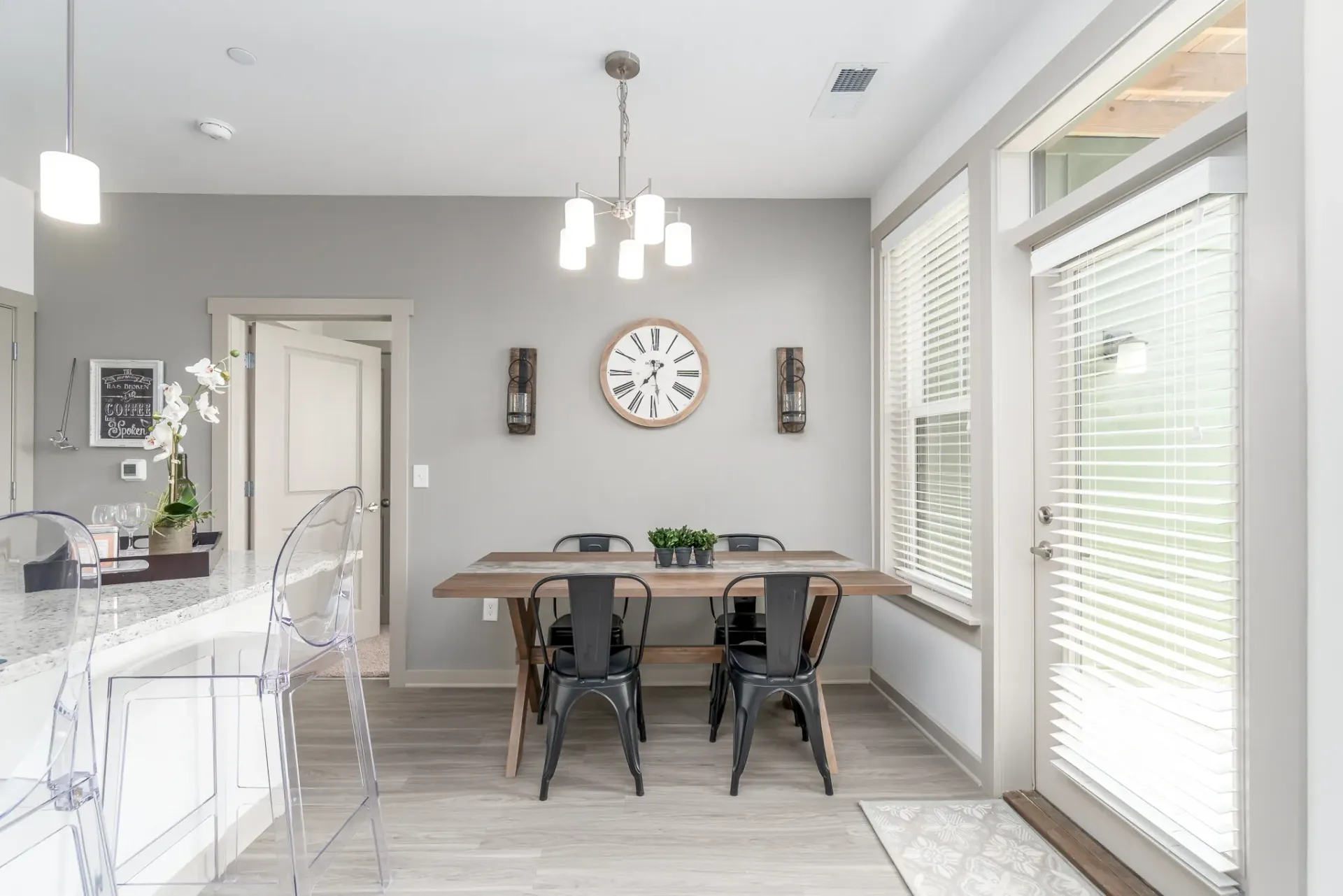 Dining area with a wooden table and four black chairs, adjacent to a kitchen counter.