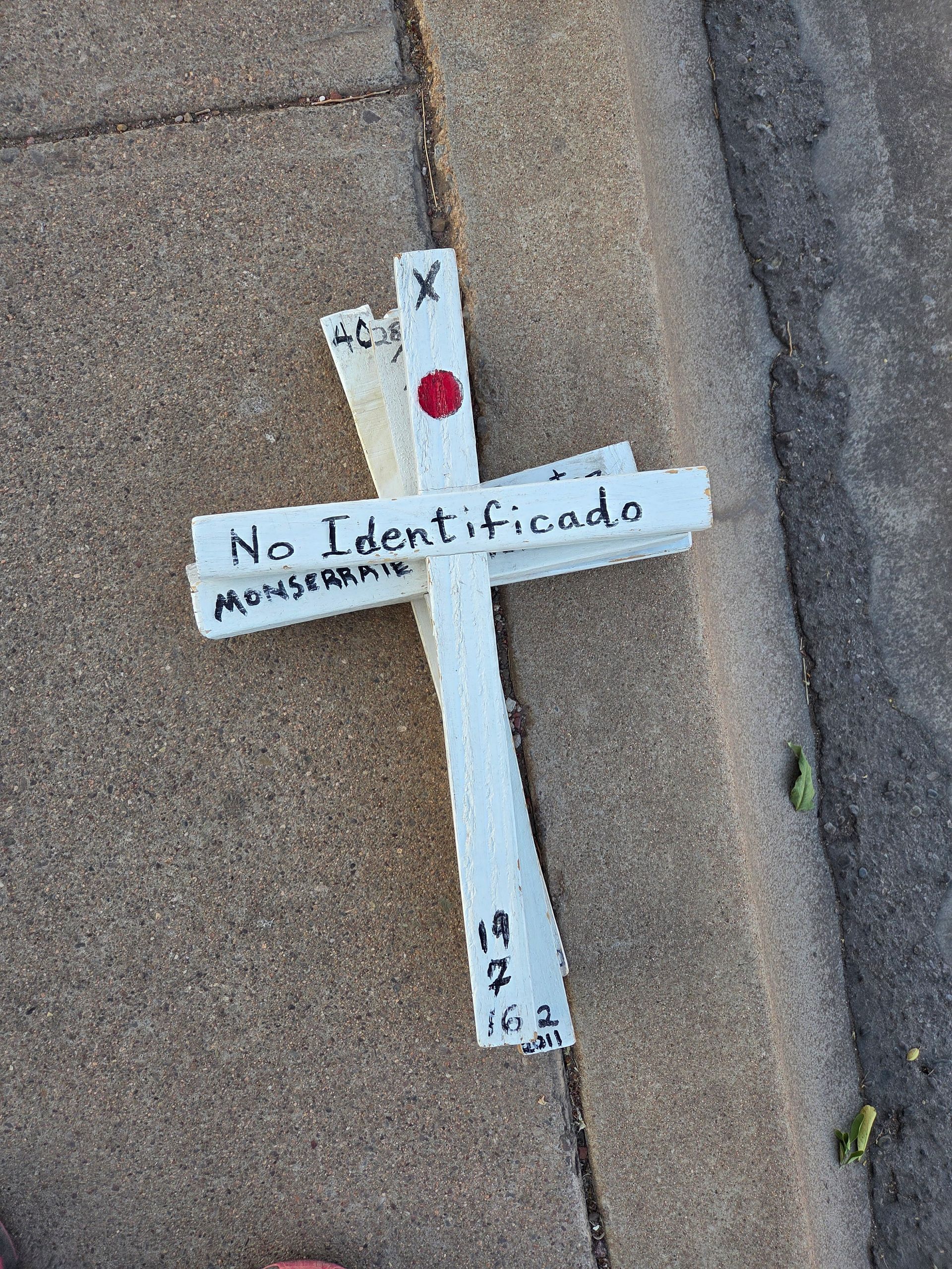 White wooden cross on pavement, inscribed