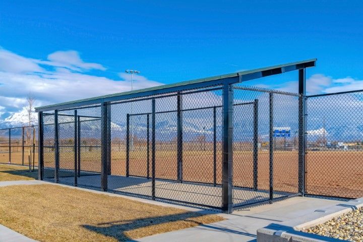 A modern, covered outdoor enclosure with chain-link fencing, situated on a concrete slab against a mountain backdrop.