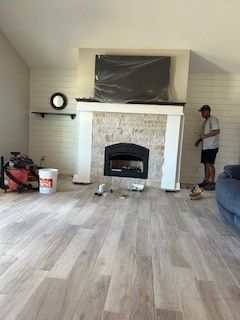 Living room with a fireplace, wood-look floor, and a person standing near the right wall