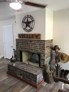 Brick fireplace with a wooden mantel, star wall decor, and rustic items in a living room