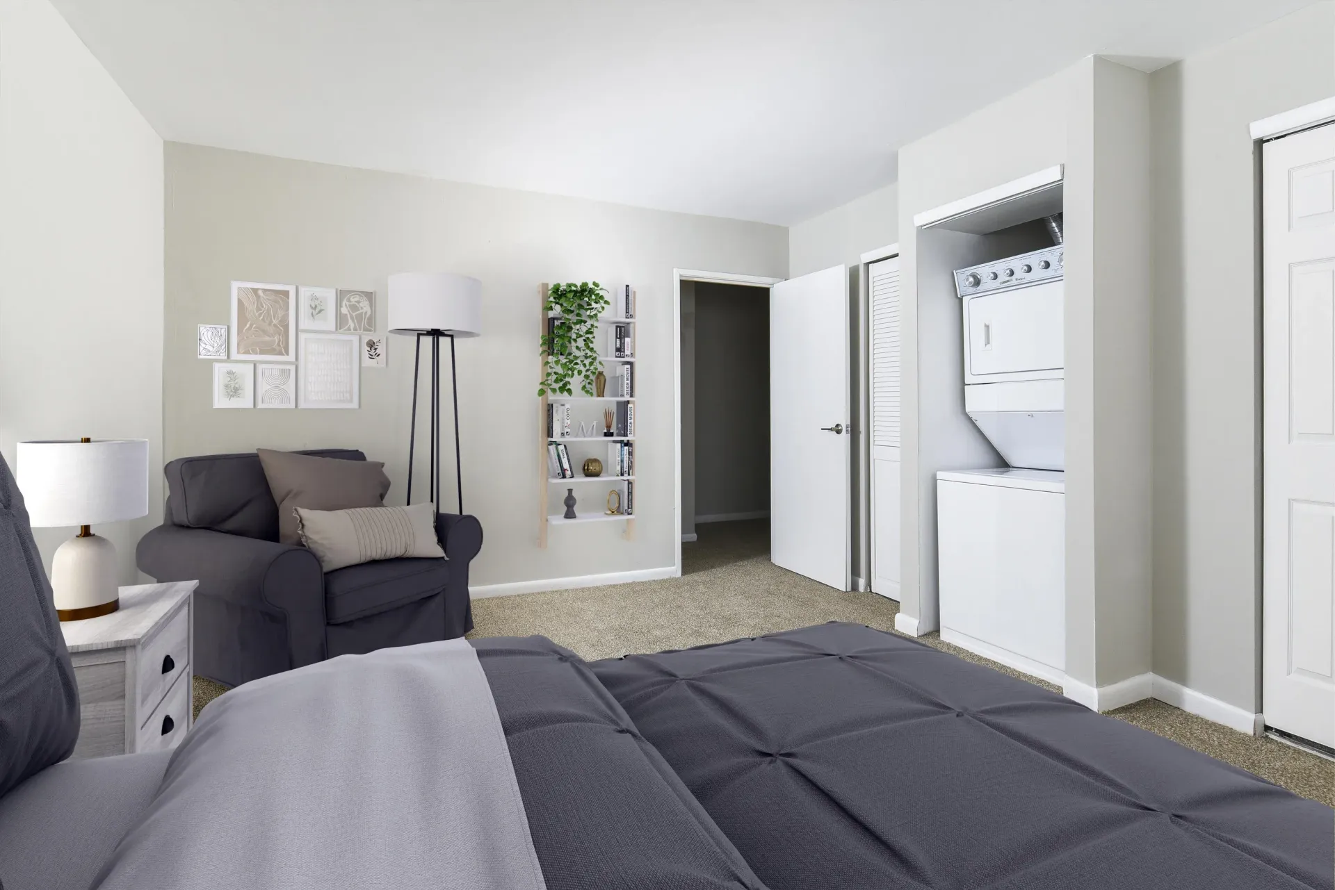 Bedroom interior with bed, recliner, and stacked washer/dryer.