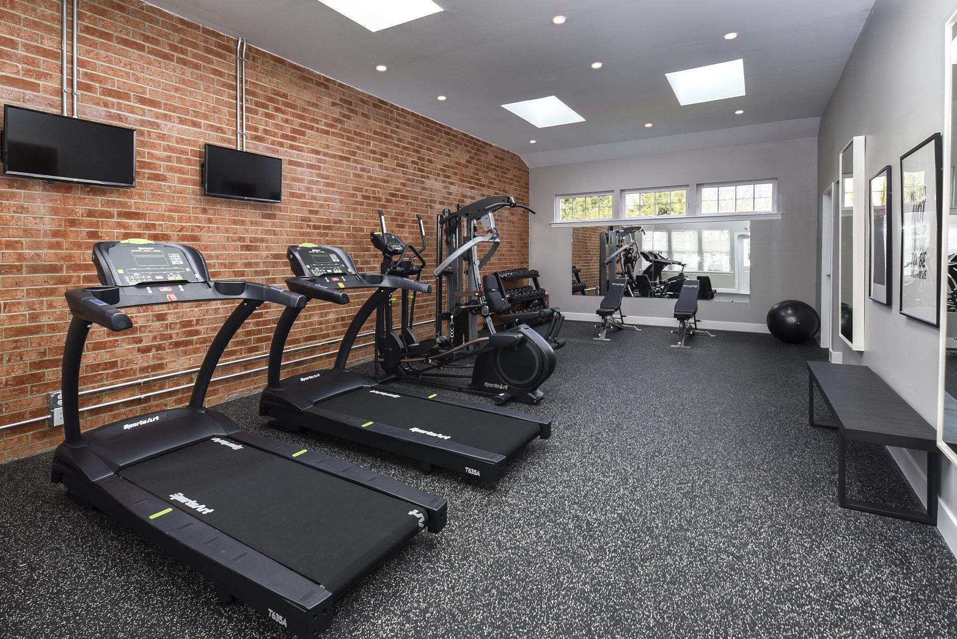 Bright community fitness center featuring treadmills, weight machines, and a mirrored wall at Holly Court, offers apartments near downtown Pitman, NJ.