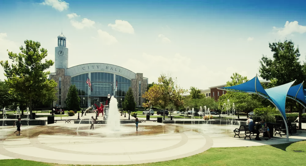 A fountain in a park with a large building in the background