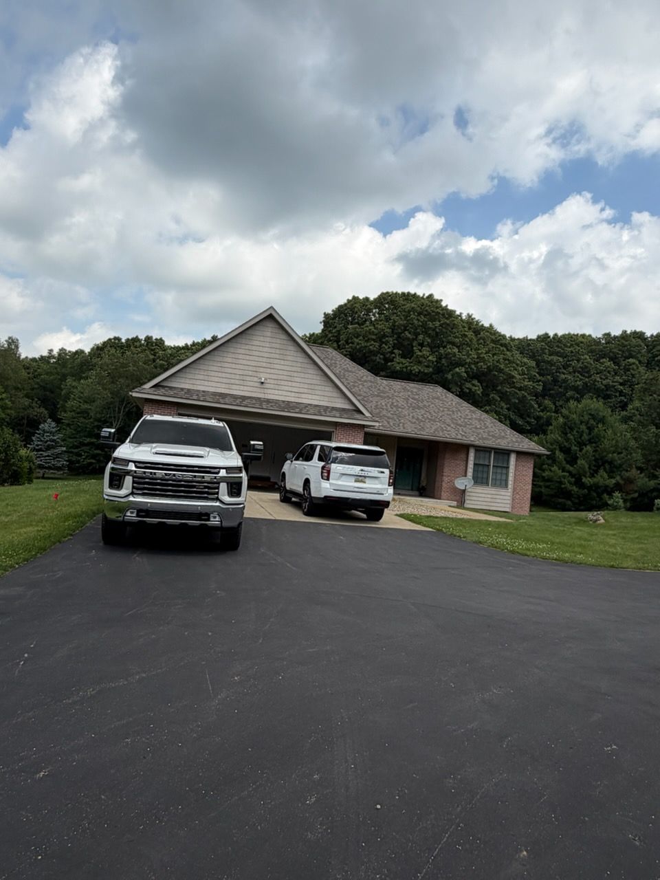 Suburban house with two white trucks parked in the driveway under a cloudy sky