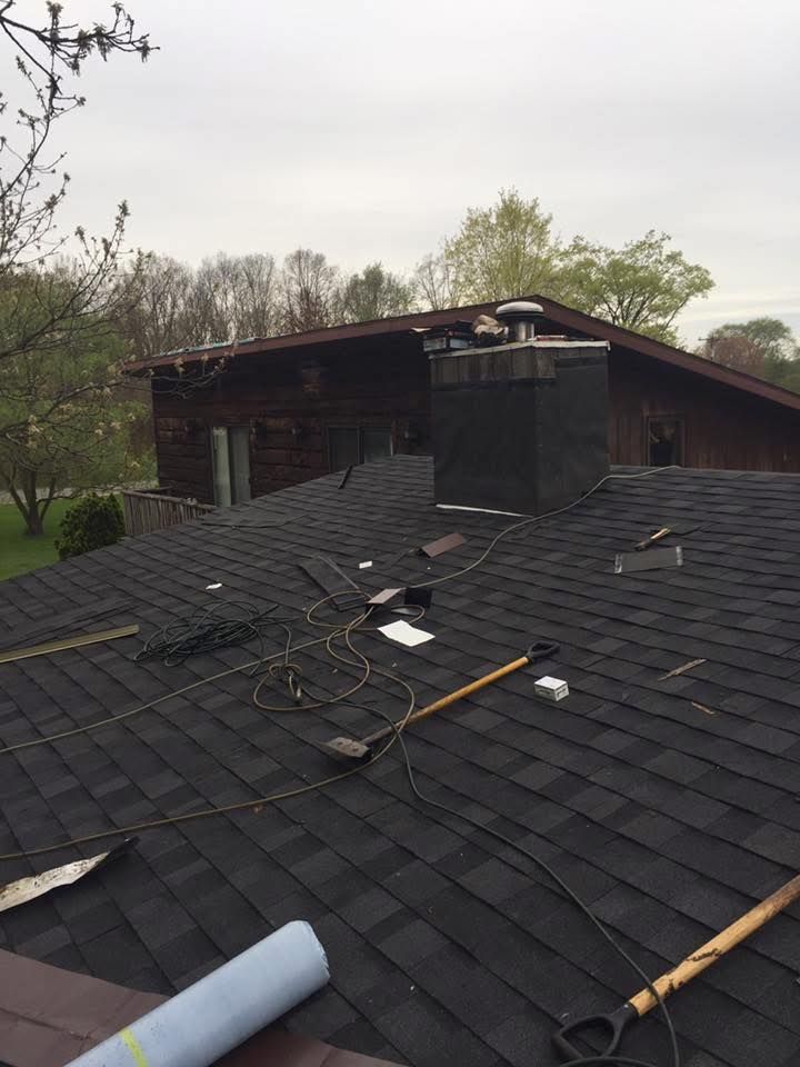 Damaged black shingle roof with exposed debris and a partially collapsed upper structure outdoors