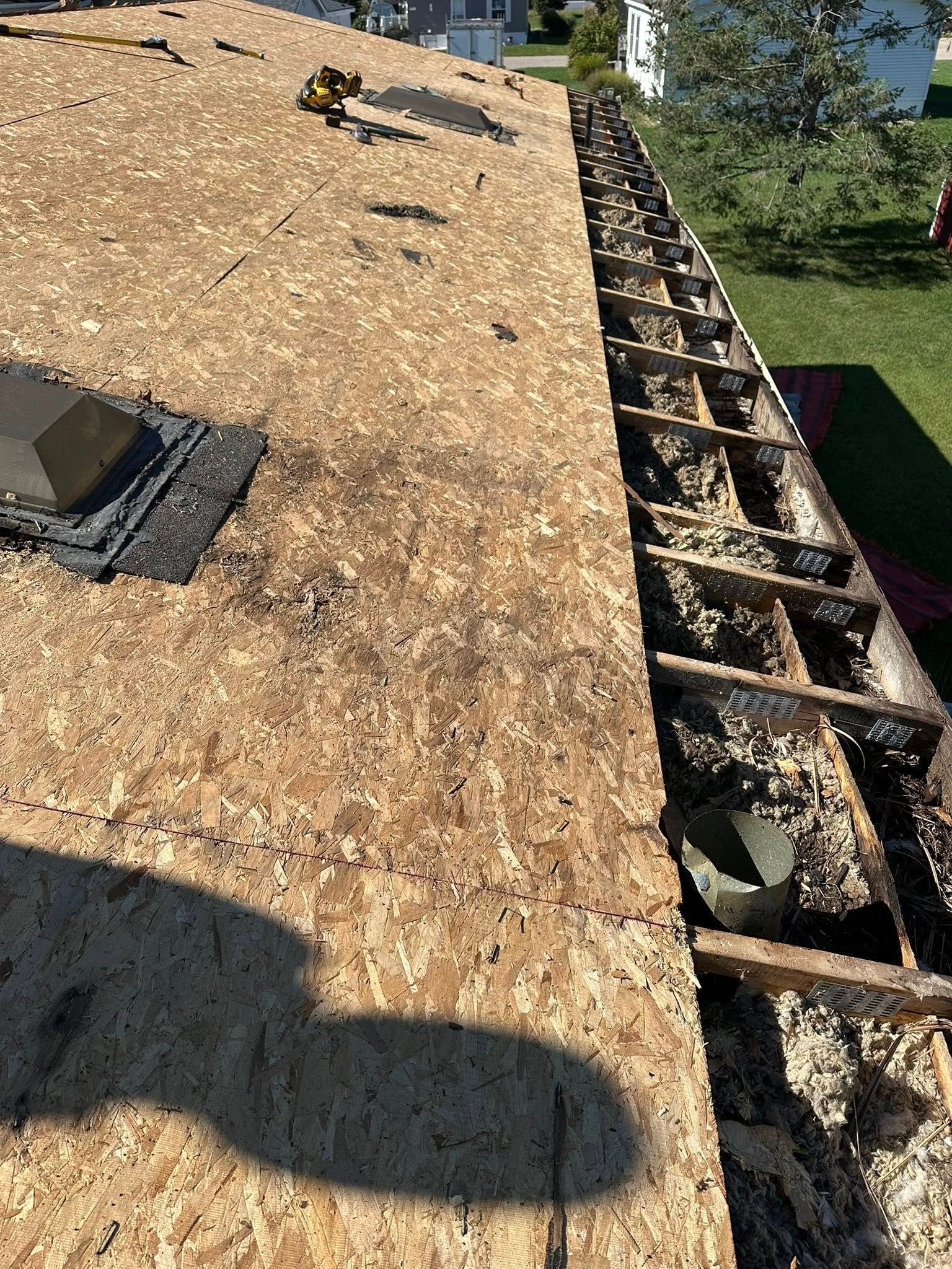 Roof under construction with exposed plywood and open edge showing roof framing and rubble below