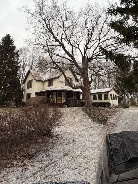 Snowy suburban house with bare trees and a dark car in the foreground