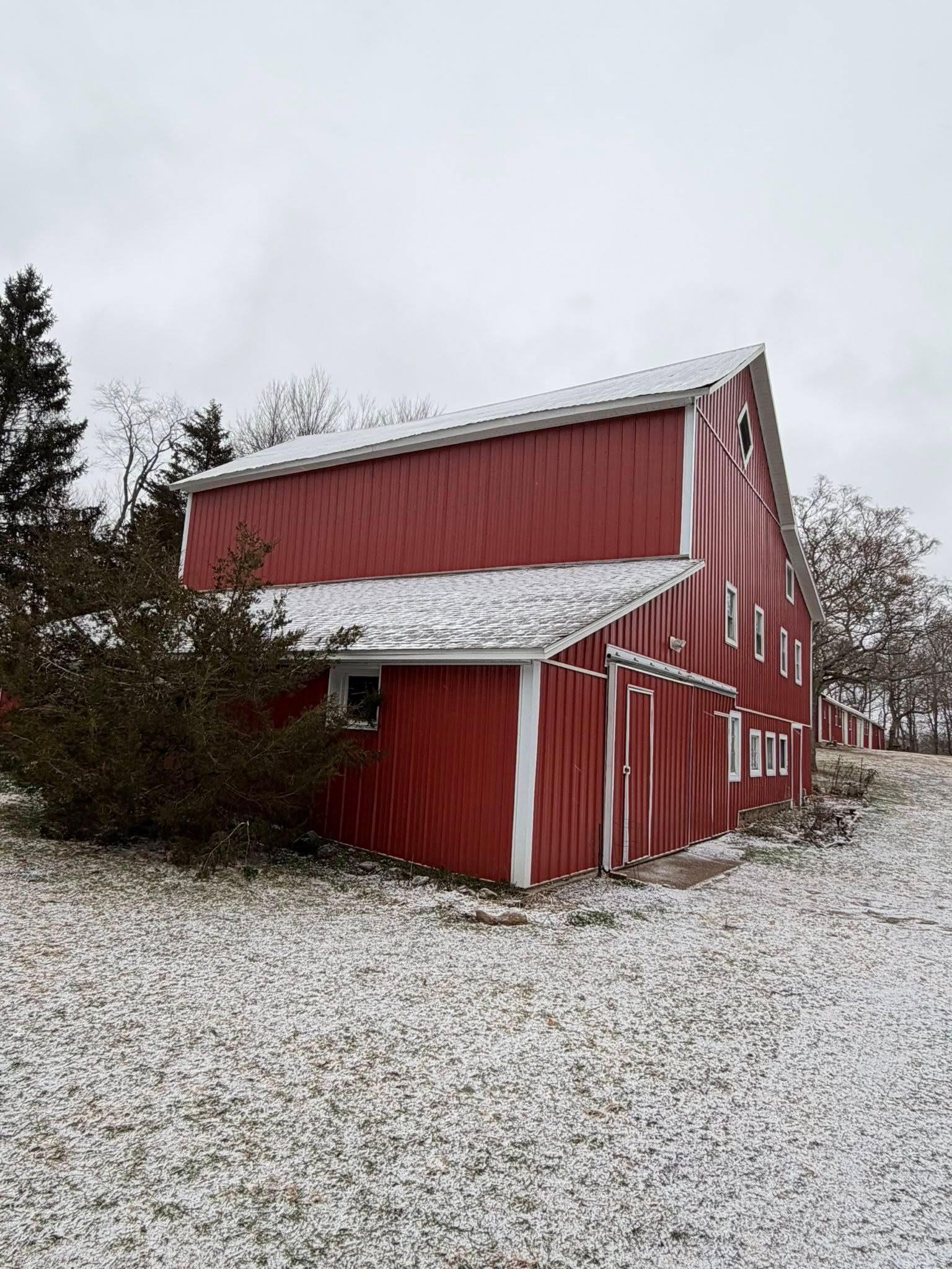 Red barn with snow on the roof in a snowy rural field