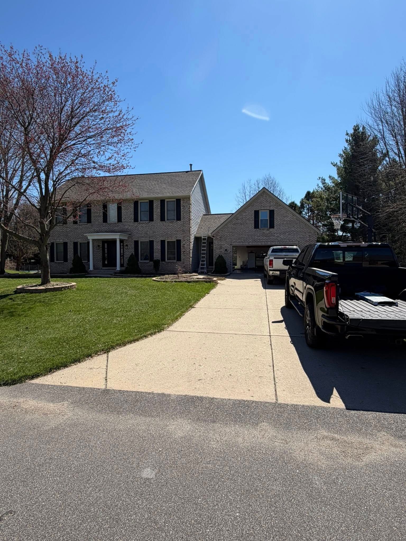 Suburban stone house with a driveway, green lawn, and a black pickup truck parked outside