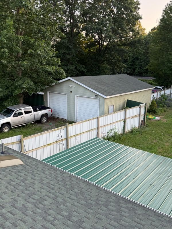 Backyard with detached garage, white fence, and white truck under trees at dusk