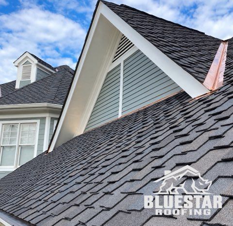 Gray shingle roof with white trim and dormer on a house under a blue sky