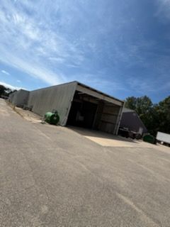 Low concrete warehouse with open bay doors under a bright blue sky