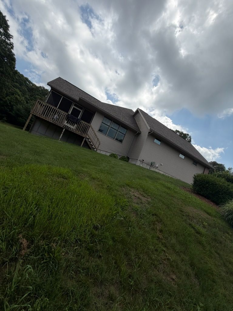 Tilted view of a beige house with a green lawn under a cloudy sky