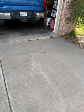 Blue pickup truck parked in a garage, with driveway and tools visible рядом