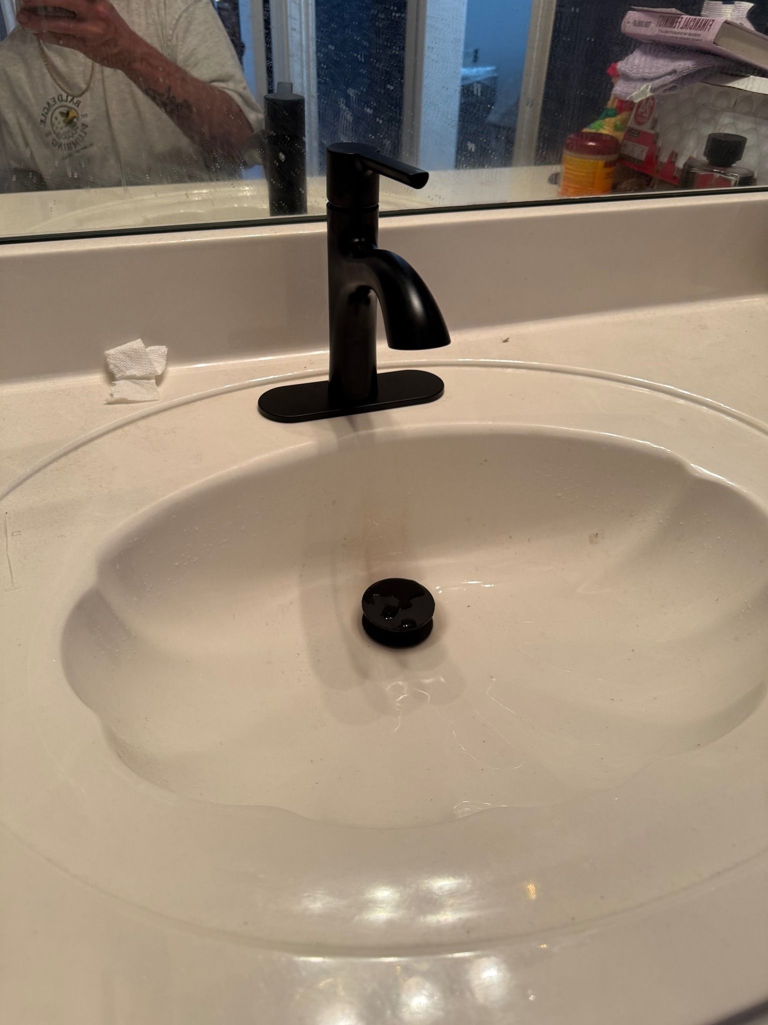 A white bathroom sink featuring a modern, matte black faucet and drain stopper.