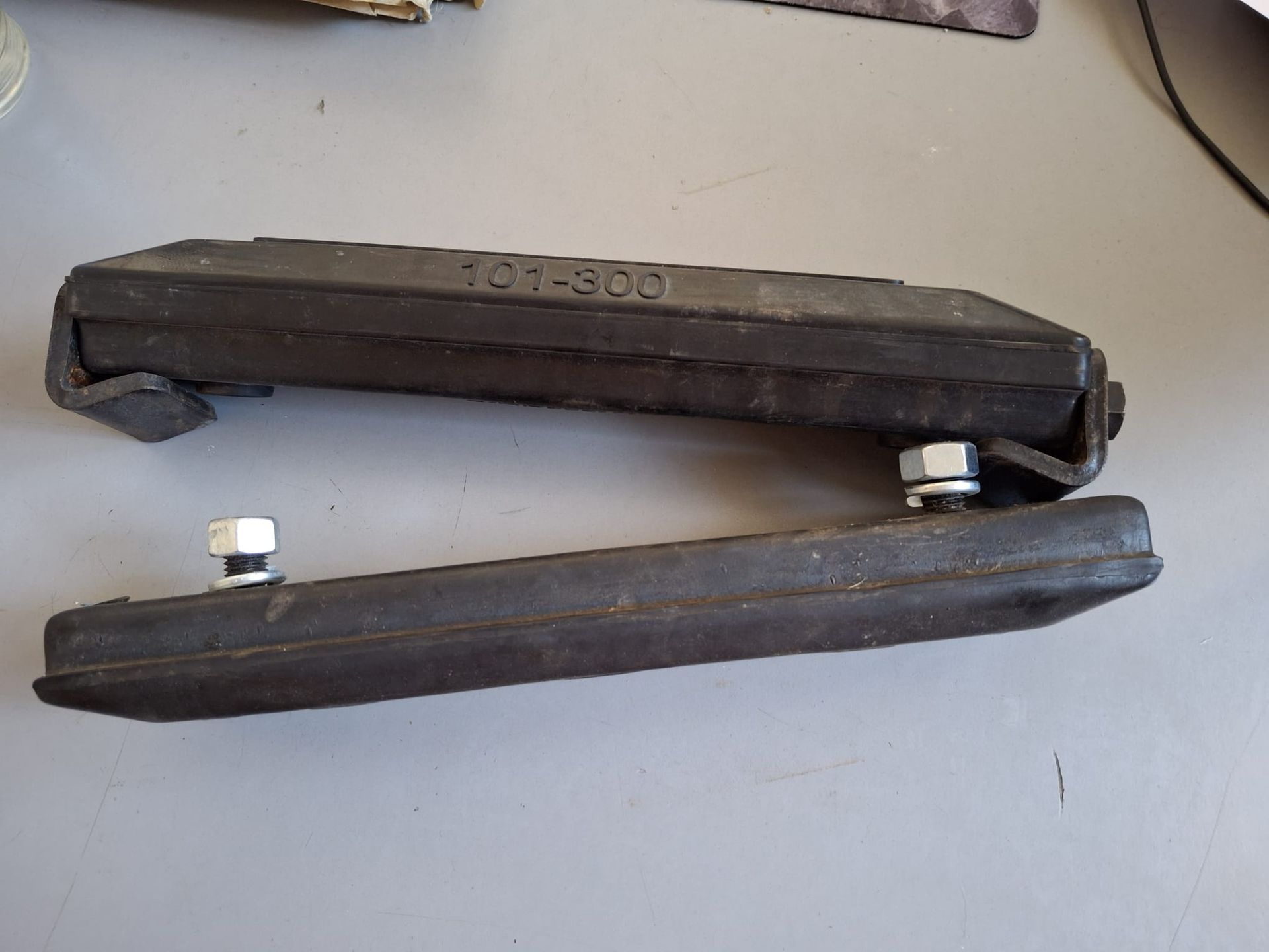 Due utensili con manico nero e ganasce metalliche, appoggiati aperti su una superficie chiara.