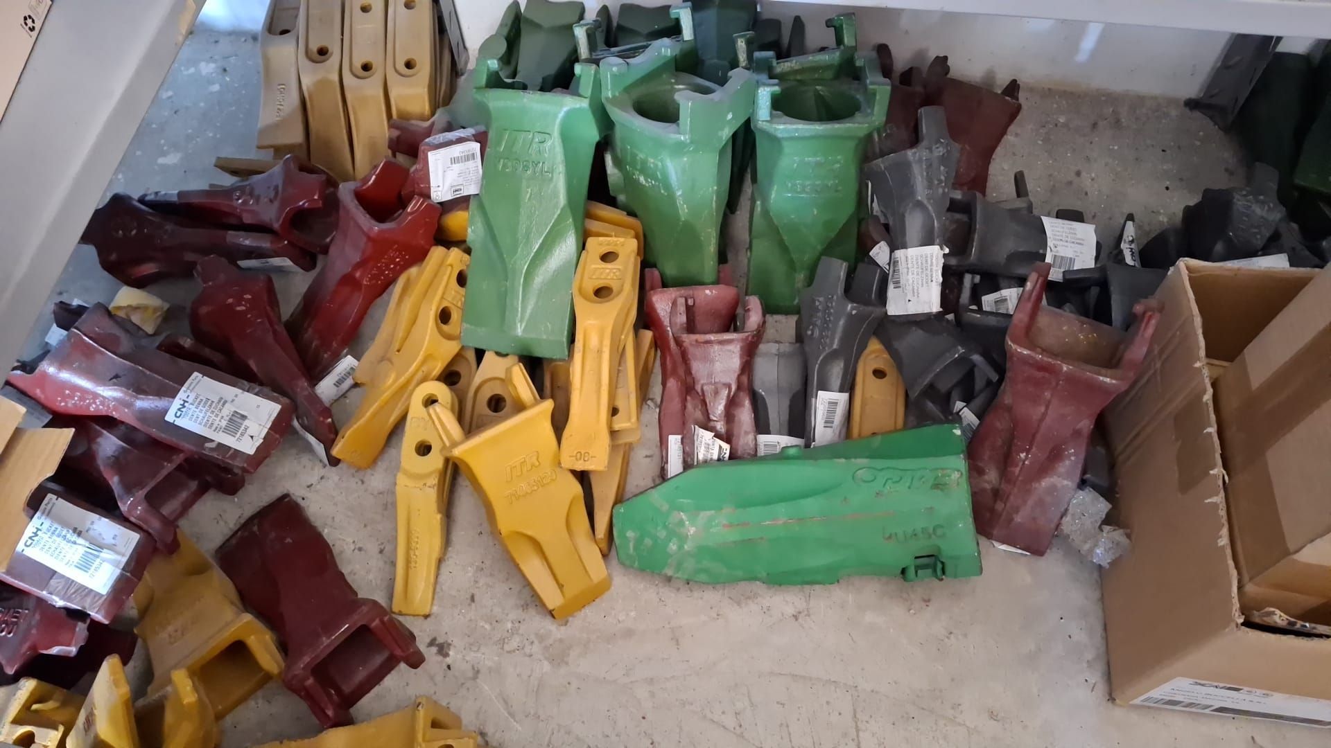Vari pezzi di metallo verdi, gialli e rossi ammucchiati in un'officina o in un magazzino.