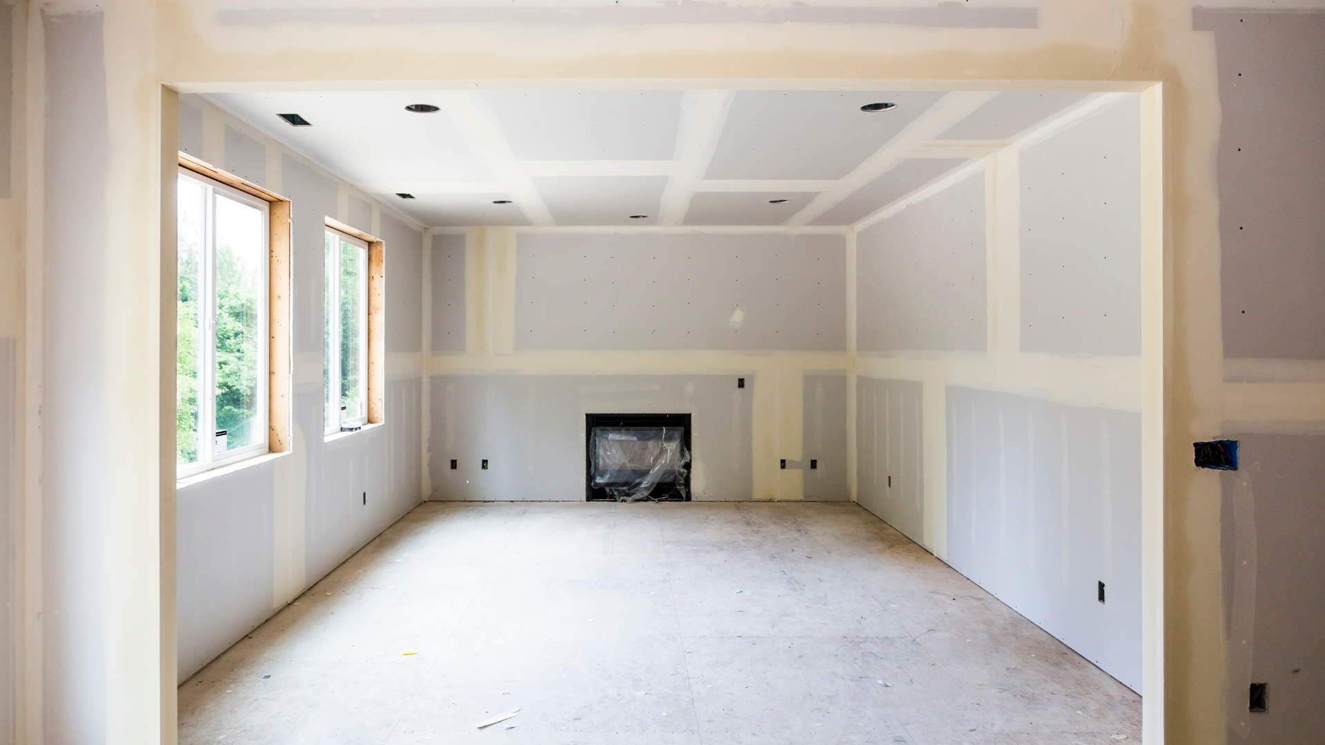 Room interior under construction with drywall and fireplace.