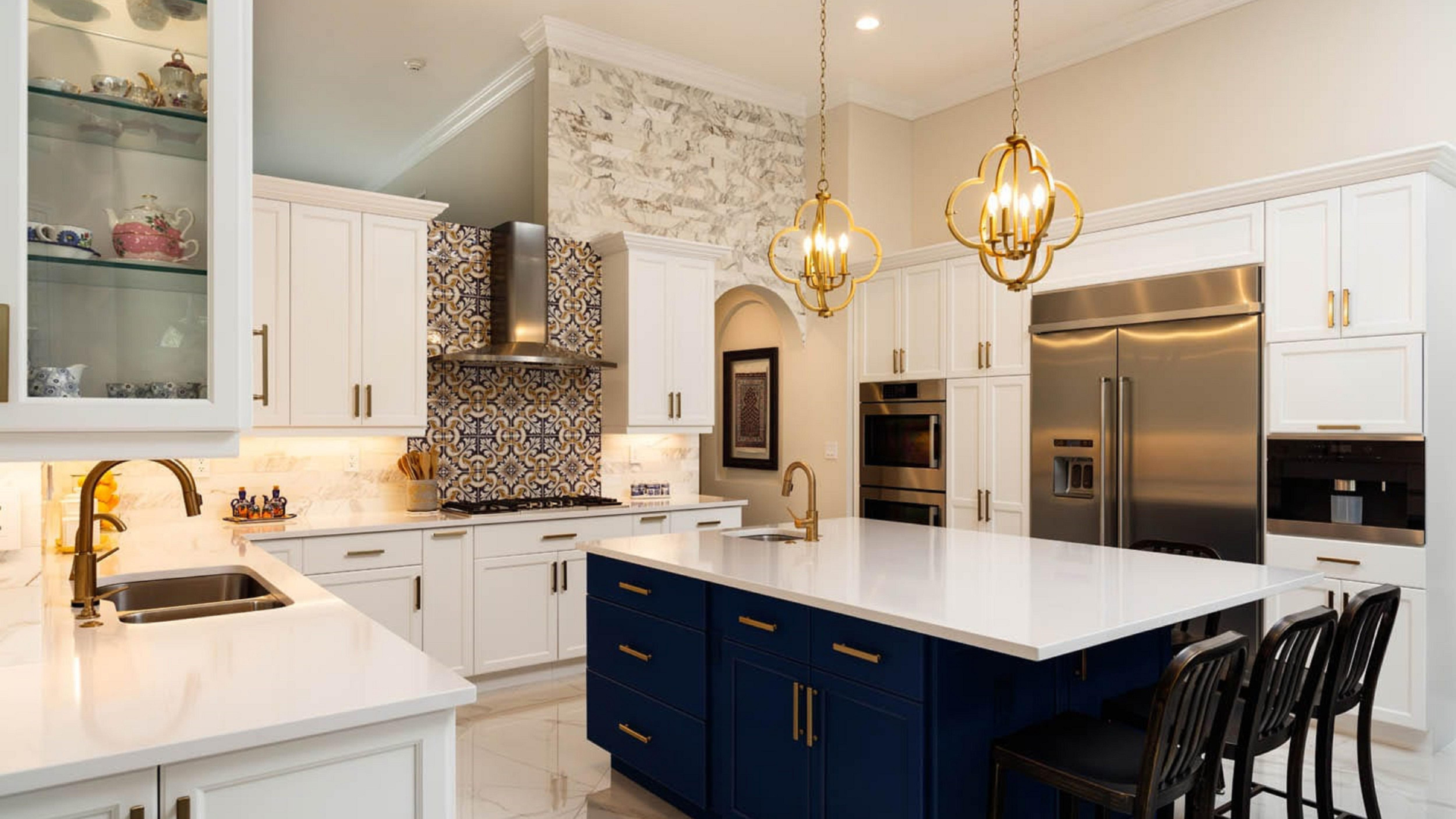 Elegant kitchen with blue island, white cabinets, gold accents, and stainless steel appliances.