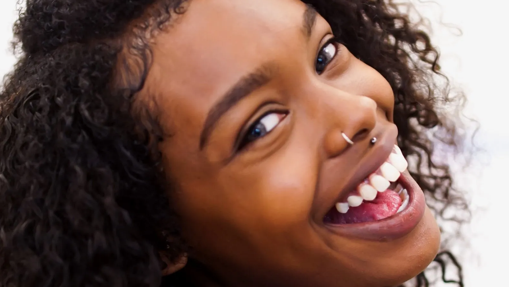 A woman with a nose ring is smiling with her mouth open.