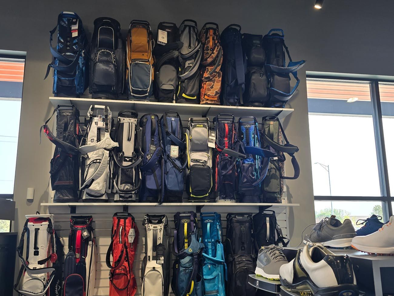 A bunch of golf bags are hanging on a wall in a store.