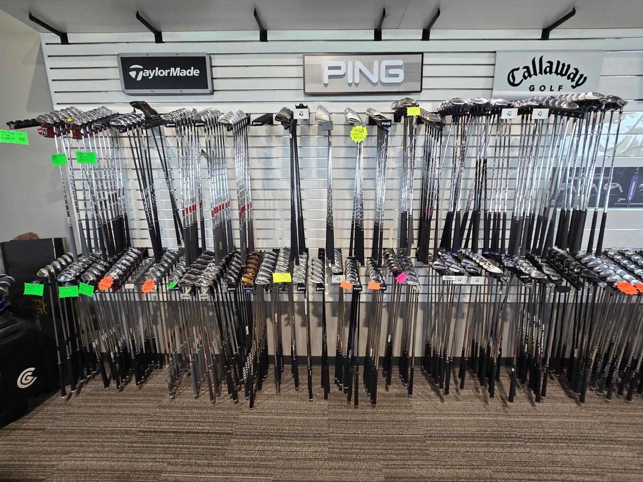 A bunch of golf clubs are hanging on a rack in a store.