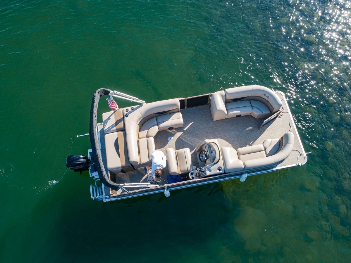Overhead view of a small beige pontoon boat floating on green water