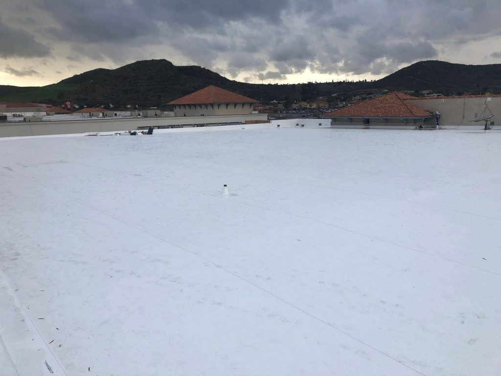 Snow-covered field with distant houses and dark hills under a cloudy sky