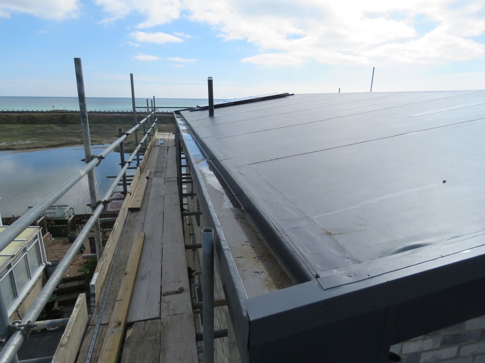 Solar panels on a rooftop beside a narrow walkway under a cloudy sky