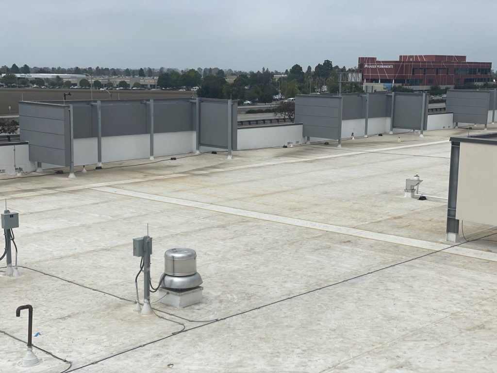 Rooftop with HVAC units and vents under a cloudy sky, with buildings in the distance