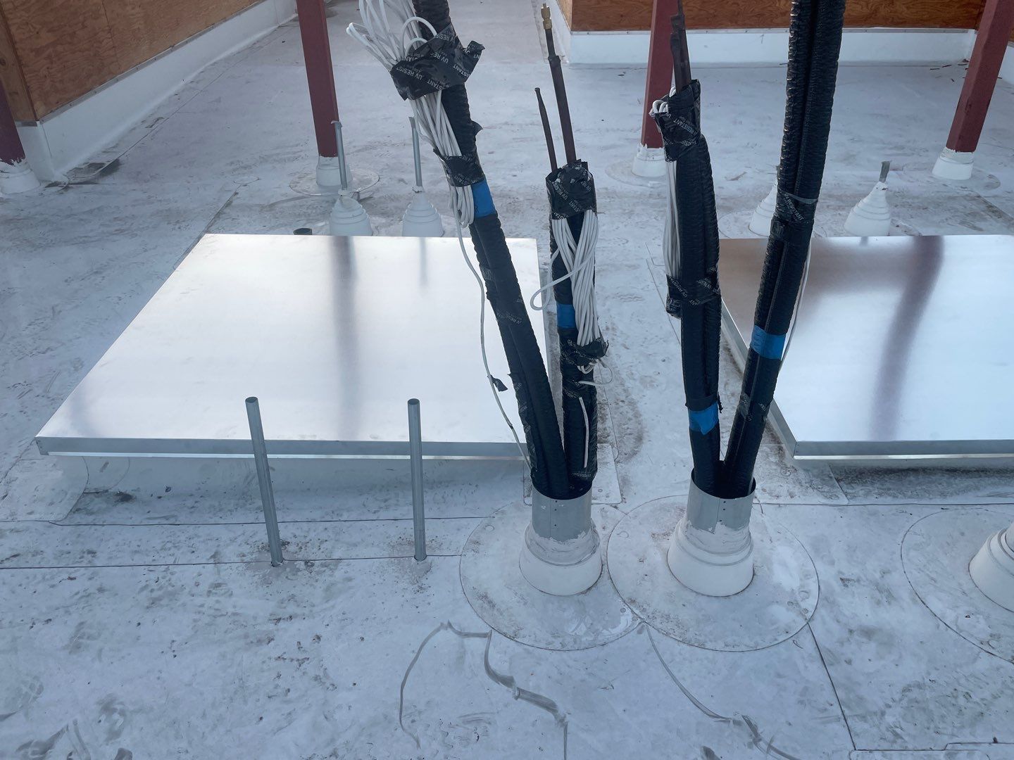 Snow-covered rooftop with cables rising from white rooftop boxes and a metal panel nearby