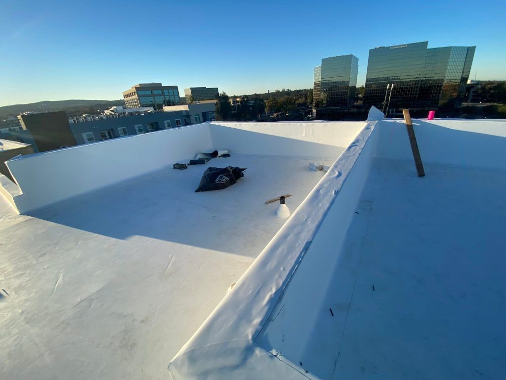 White rooftop with two vents and a city skyline in the distance at sunset