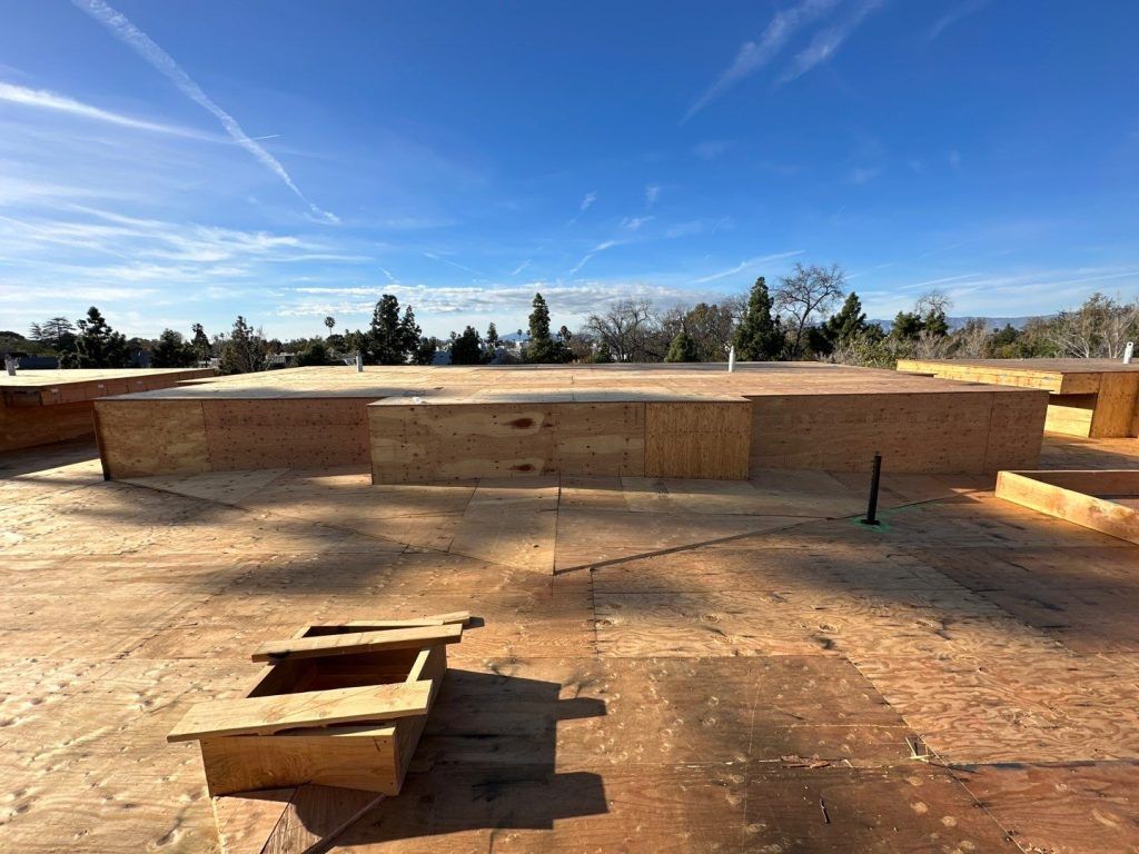 Outdoor construction site with raised concrete foundation walls under a clear blue sky