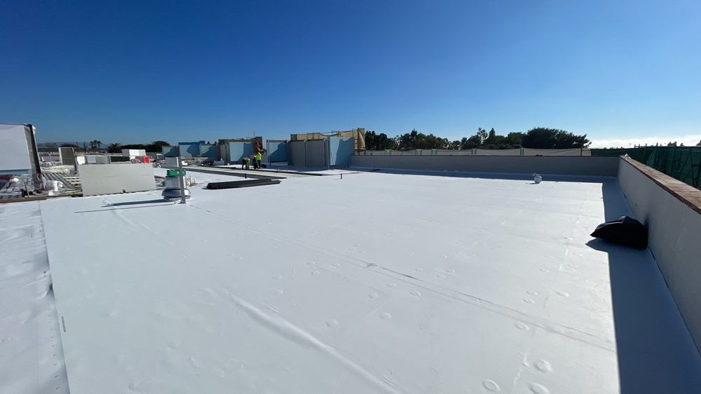 Snow-covered rooftop under a clear blue sky, with distant buildings along the horizon.