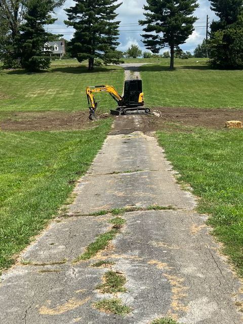 A yellow excavator is digging a hole in the middle of a dirt road.