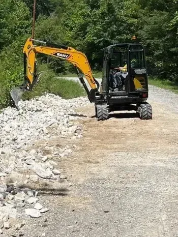 A small excavator is driving down a dirt road.