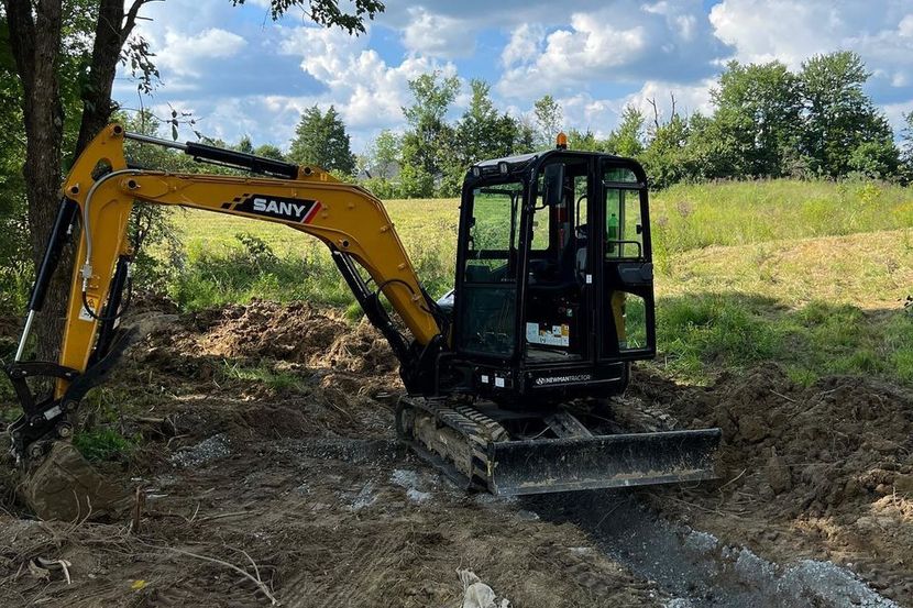 a small excavator is digging a hole in the dirt in a field .