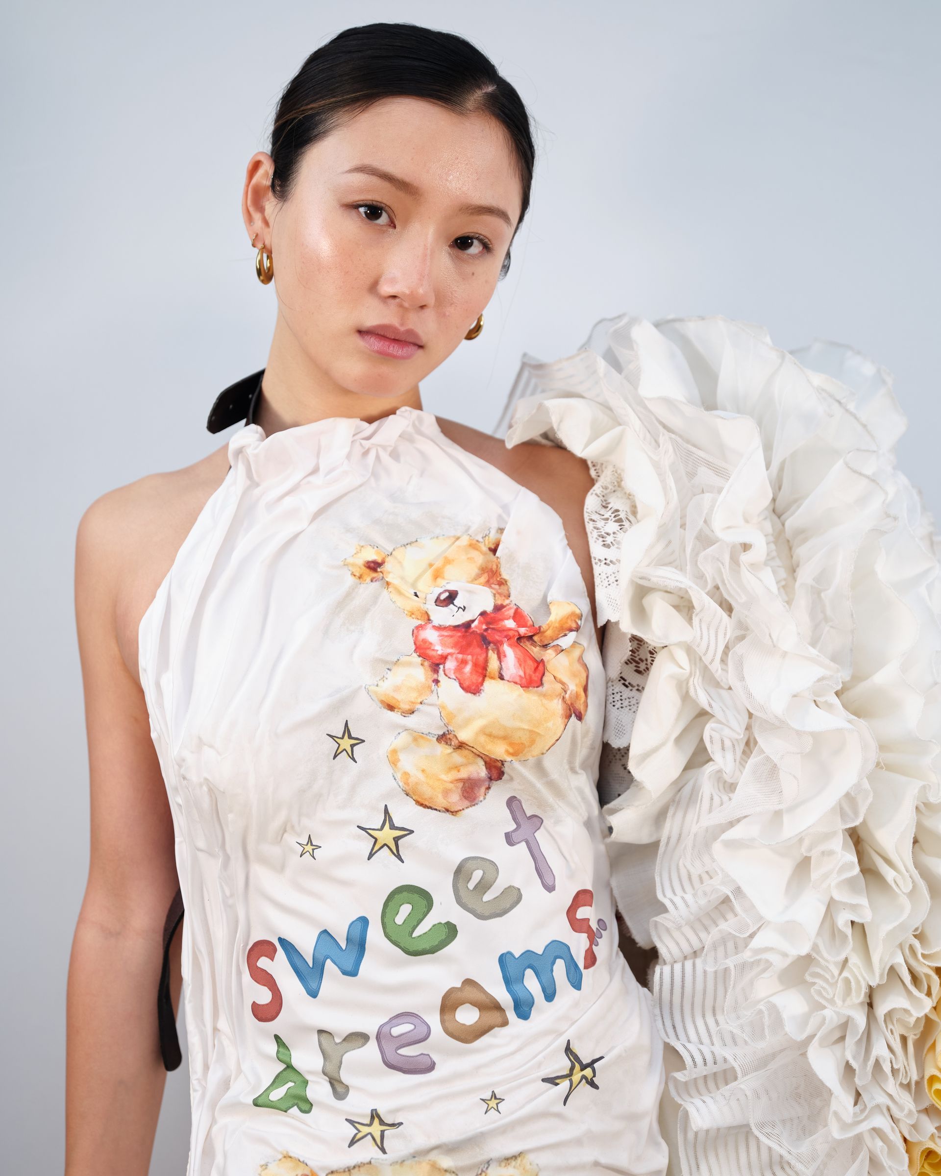 A woman is wearing a white dress with a teddy bear on it.
