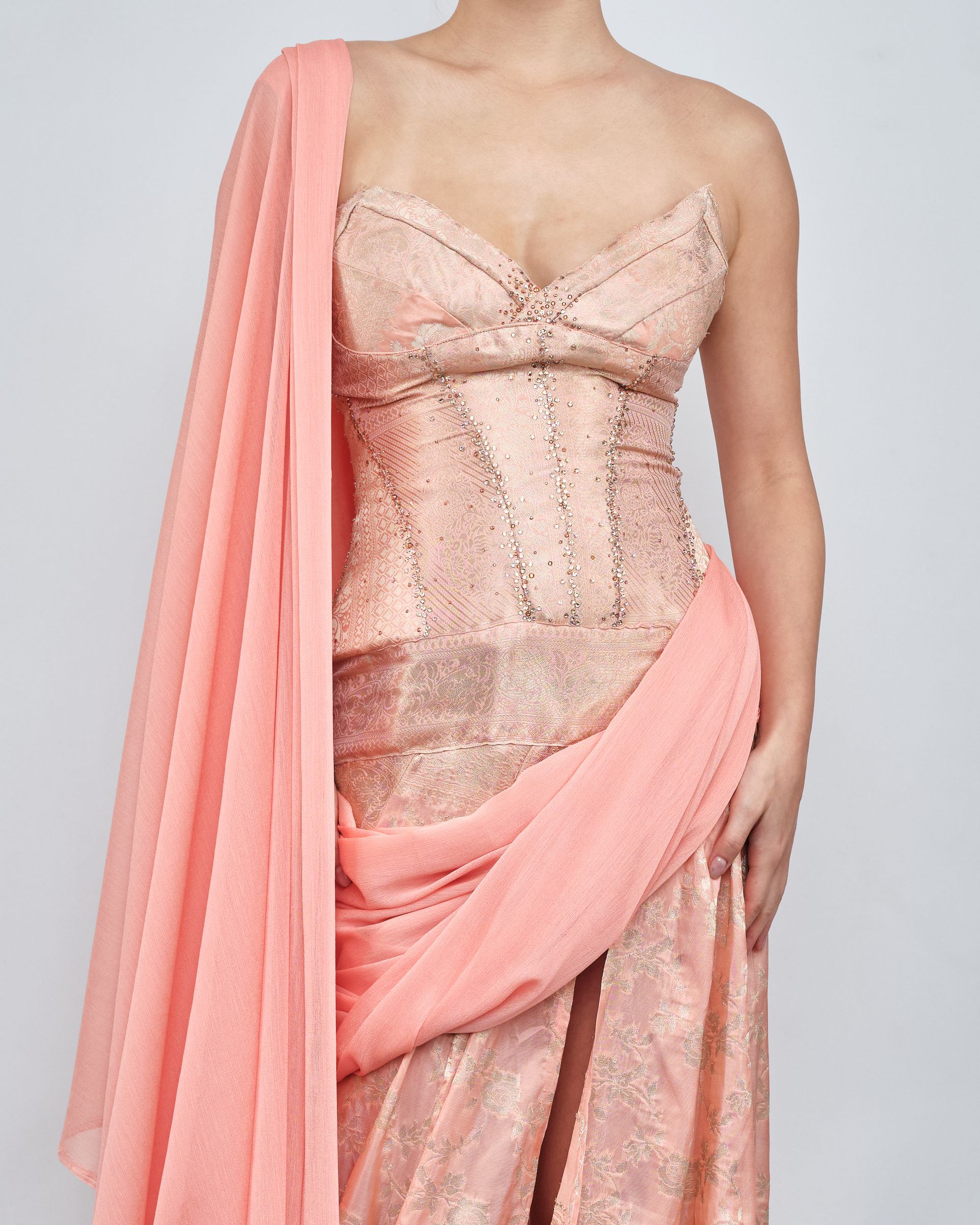 A woman is wearing a pink dress with a pink scarf around her shoulder.