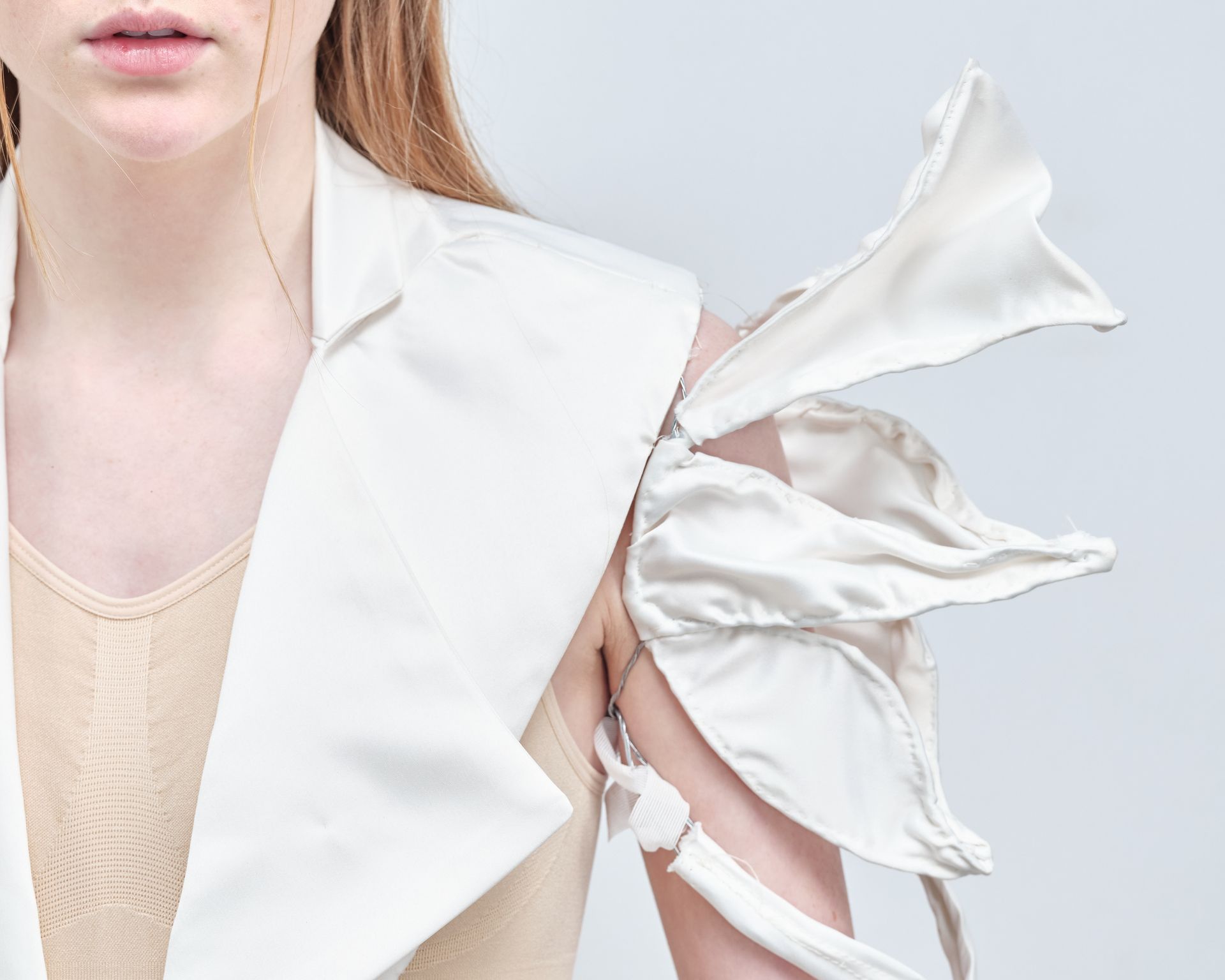 A woman is wearing a white jacket with a flower on the sleeves.