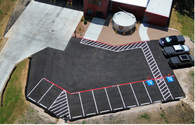 Aerial view of a parking lot with marked accessible spaces beside a building and circular structure.
