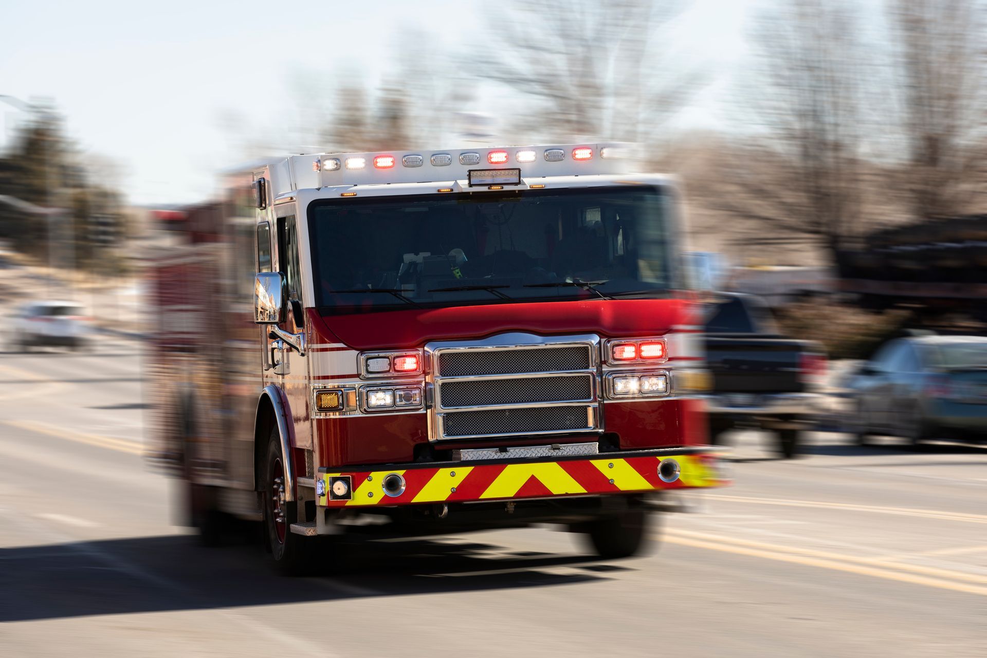 Red and white ambulance speeding down a road with lights flashing.