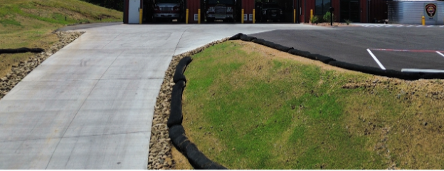 Concrete driveway entrance beside a grassy curb and paved parking lot at a building