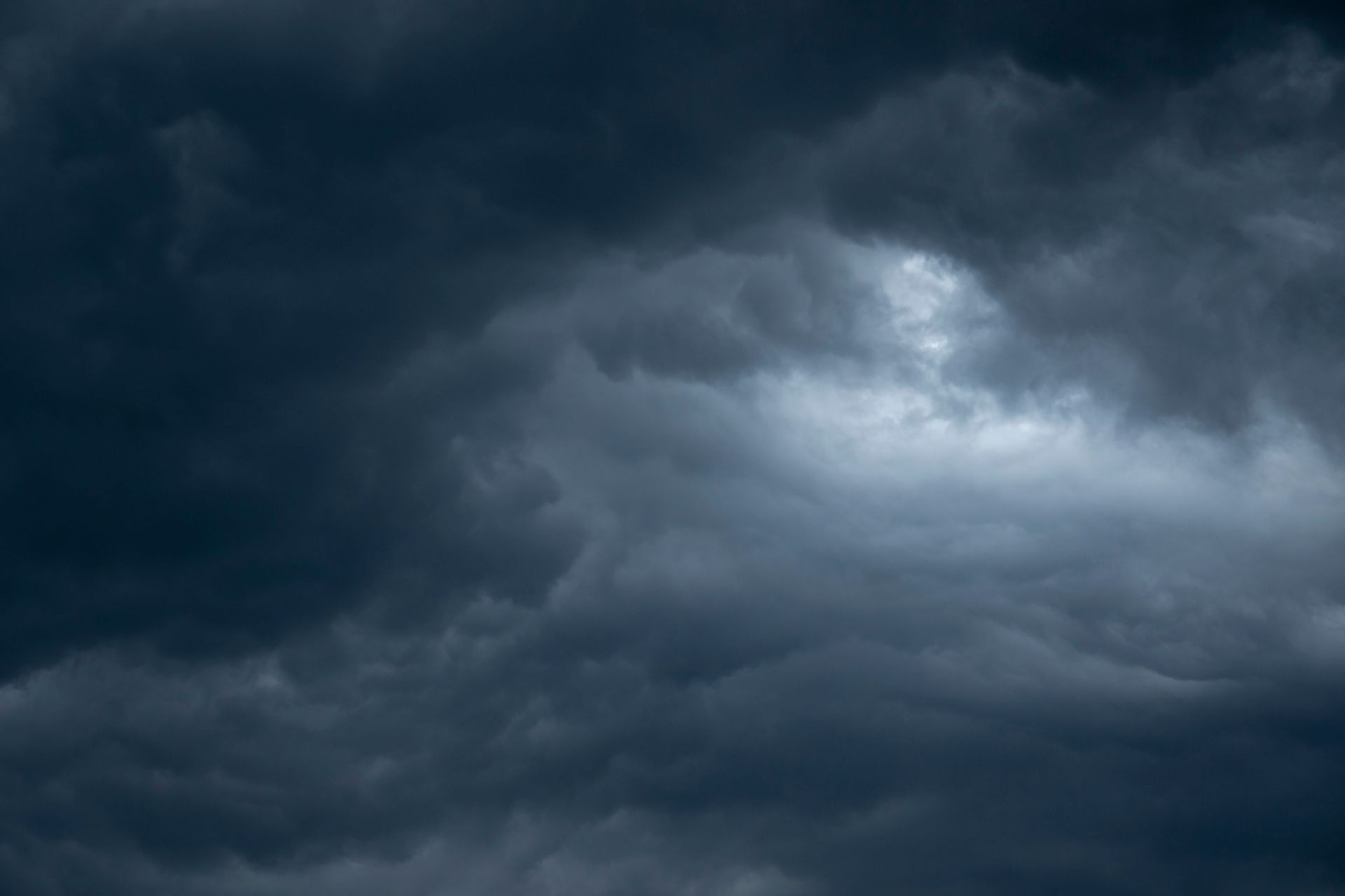 Dark, stormy clouds filling the sky with a bright opening near the center