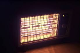 A heater is sitting on a wooden floor in a dark room.
