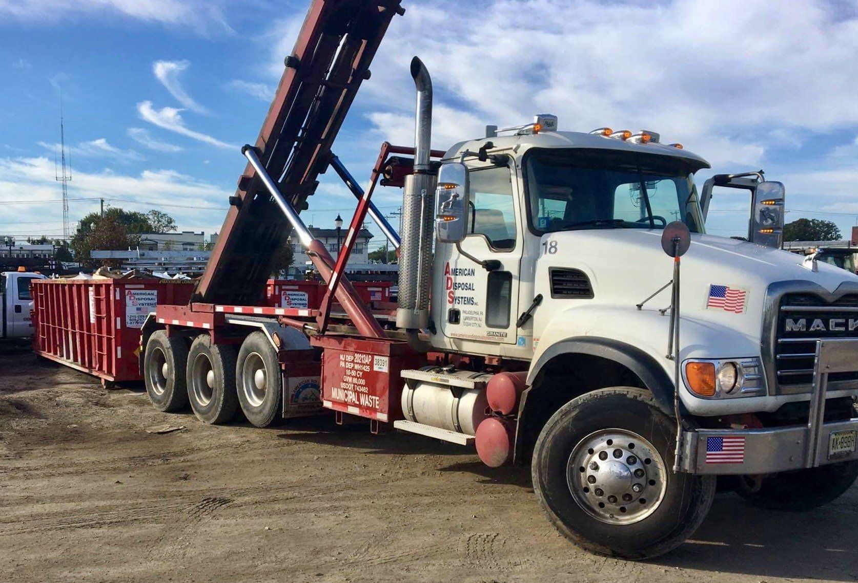 A mack dump truck is parked in a dirt lot